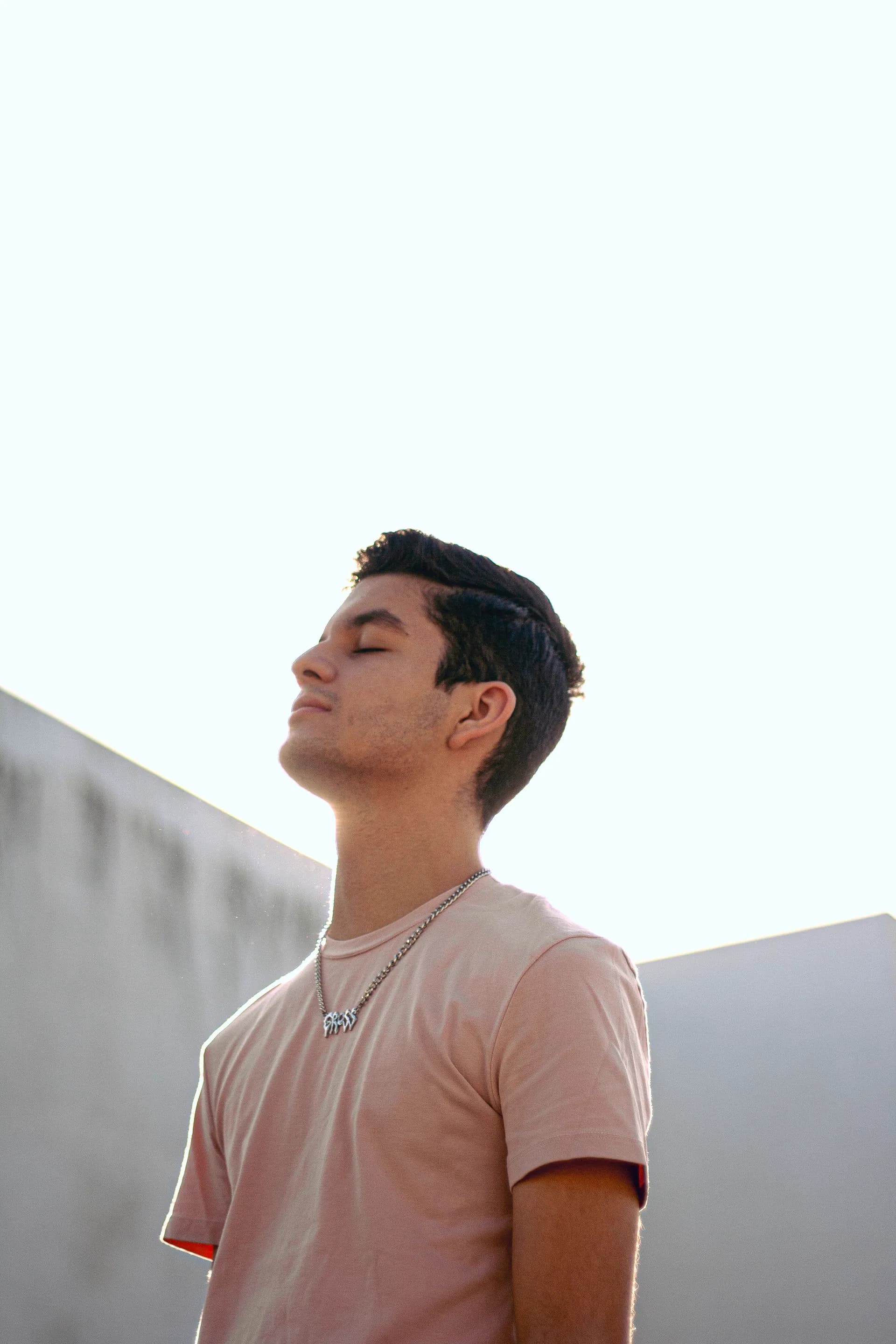 A teenager in profile, eyes closed, against the light