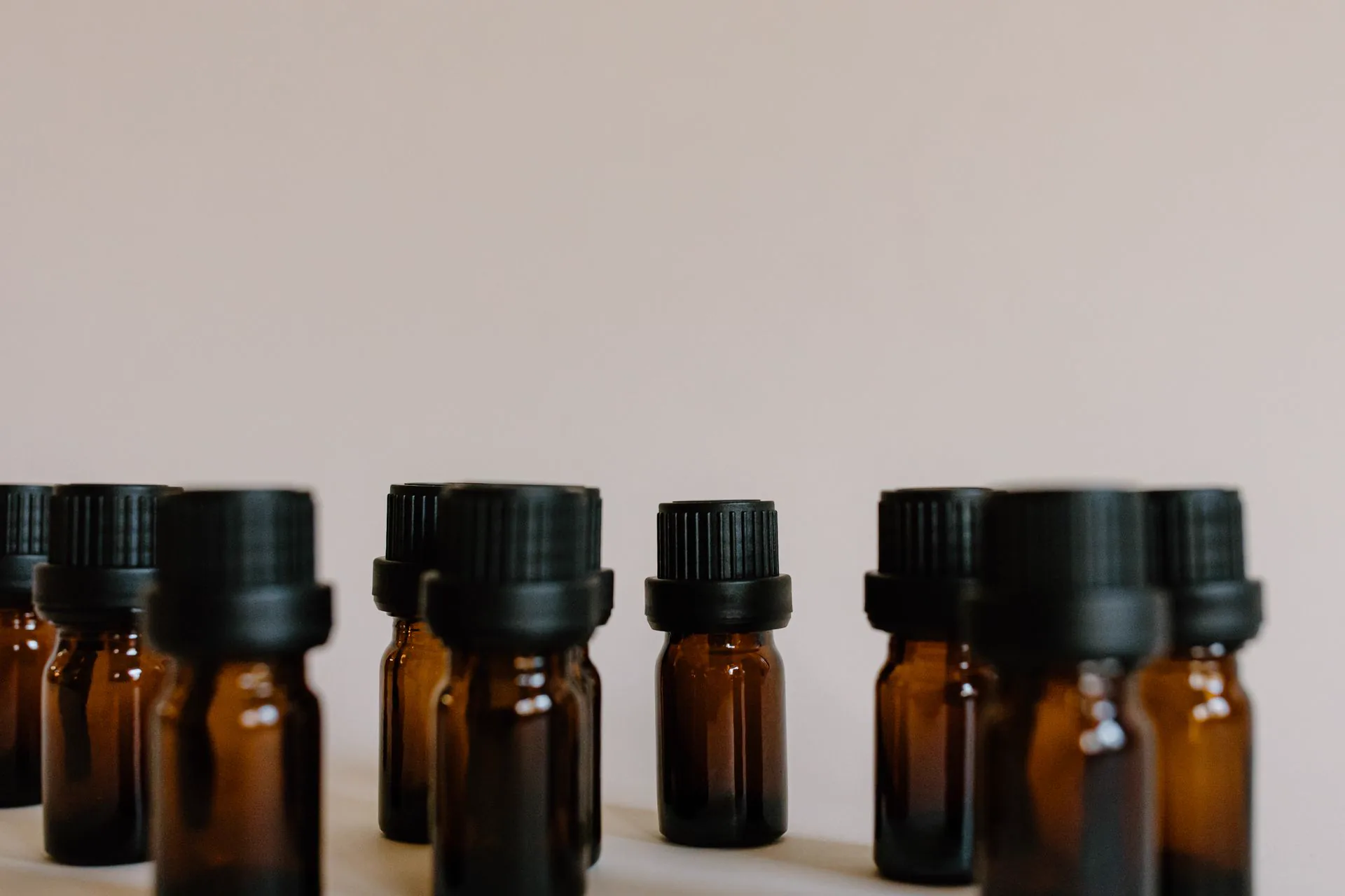 Amber glass bottles lined up on a pale surface, in a soft light