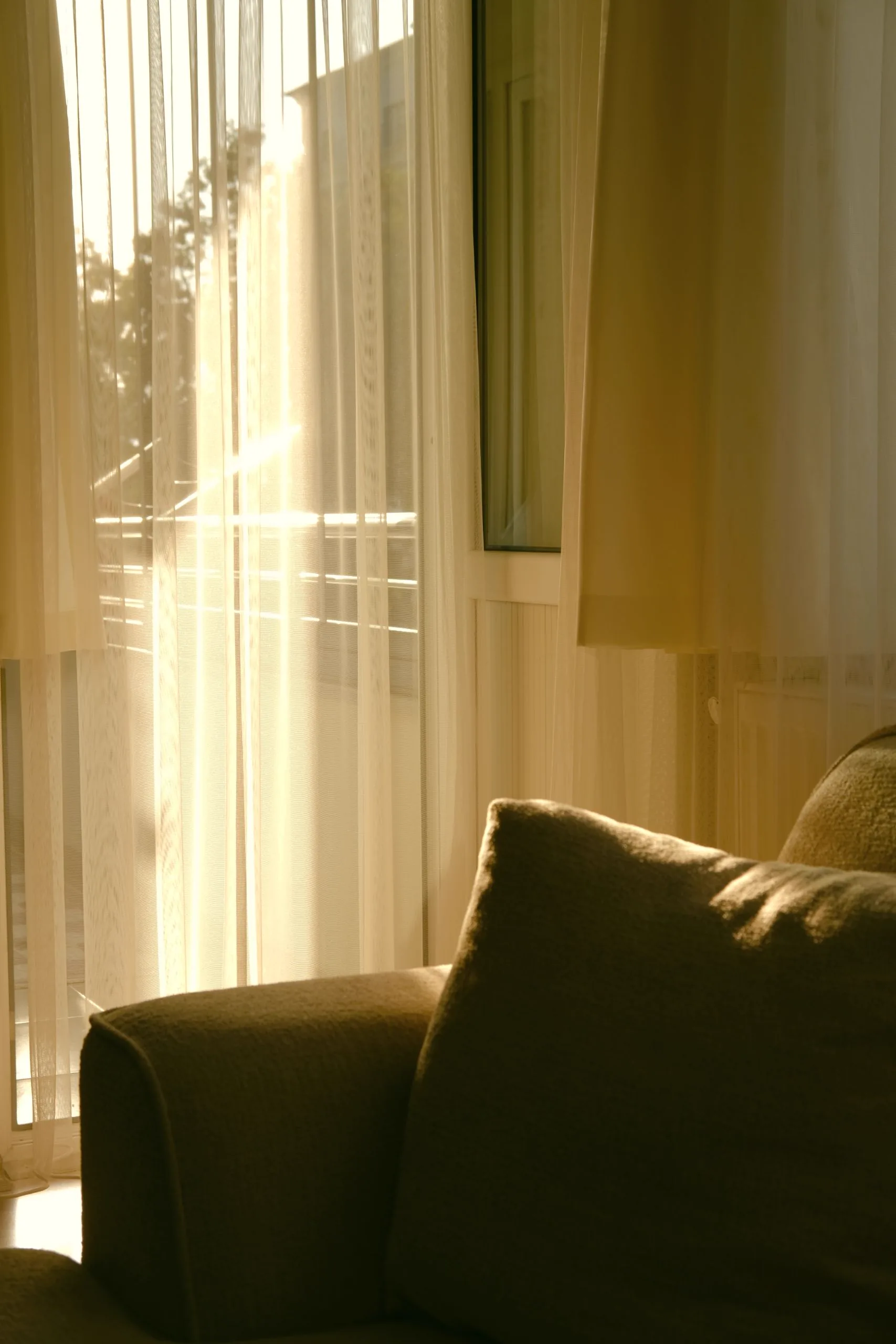 A linen curtain in front of a French window, the light filtered through it